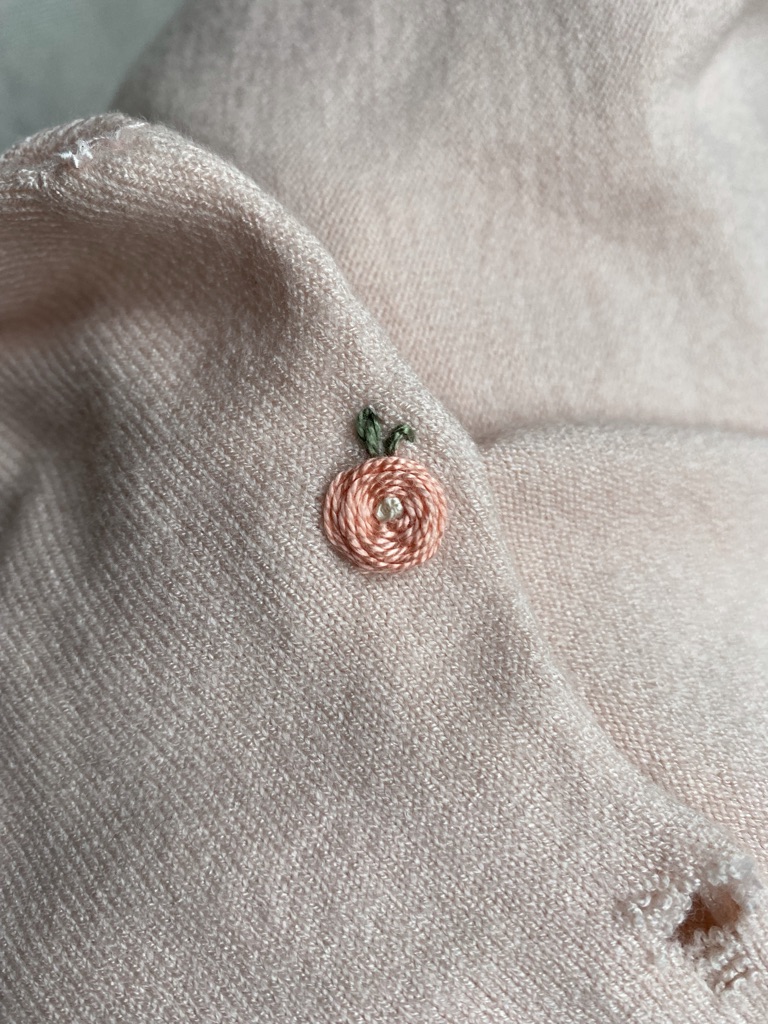 visibly mending a peach poncho with embroidery  