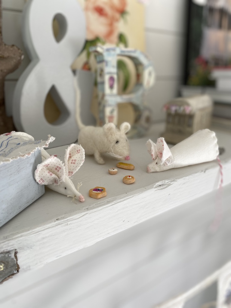 three homemade fabric mice sit on playroom shelf eating pretend food