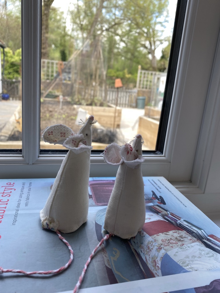 two sweet white fabric mice sit on top of books looking out of window