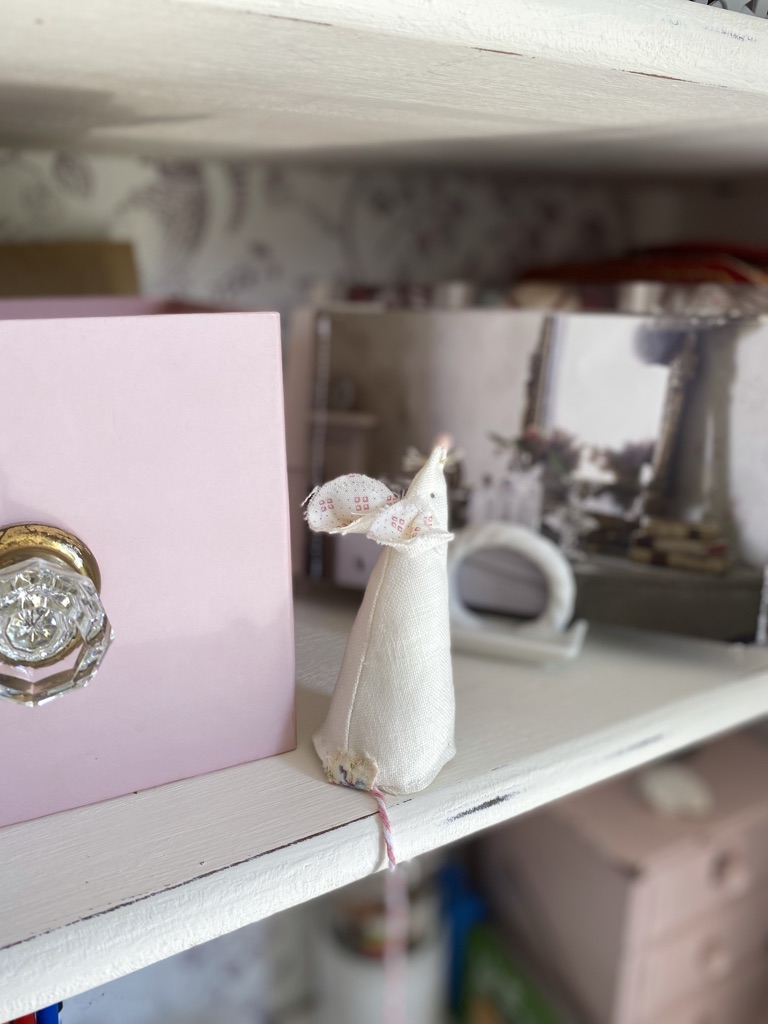 white homemade fabric mouse on craft shelf next to pink box