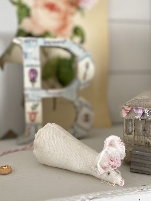 pretty white fabric mouse sits on toy shelf with decoupage letter B