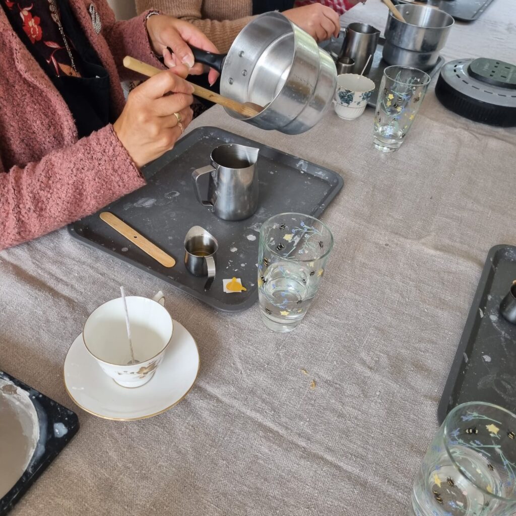 lady pours wax to make candle in tea cup