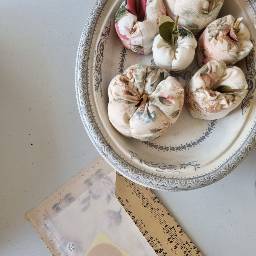 photo from above of fabric apples and pumpkins in vintage pot with music paper and vellum envelope