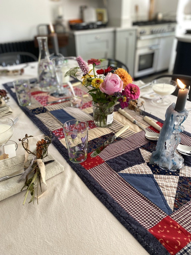 colourful table setting for lunch with homespun runner and jam jar flowers and candles