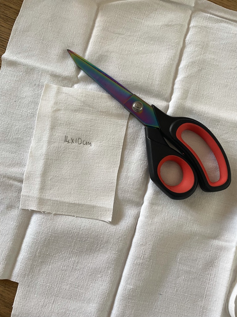 white linen fabric and black and red scissors