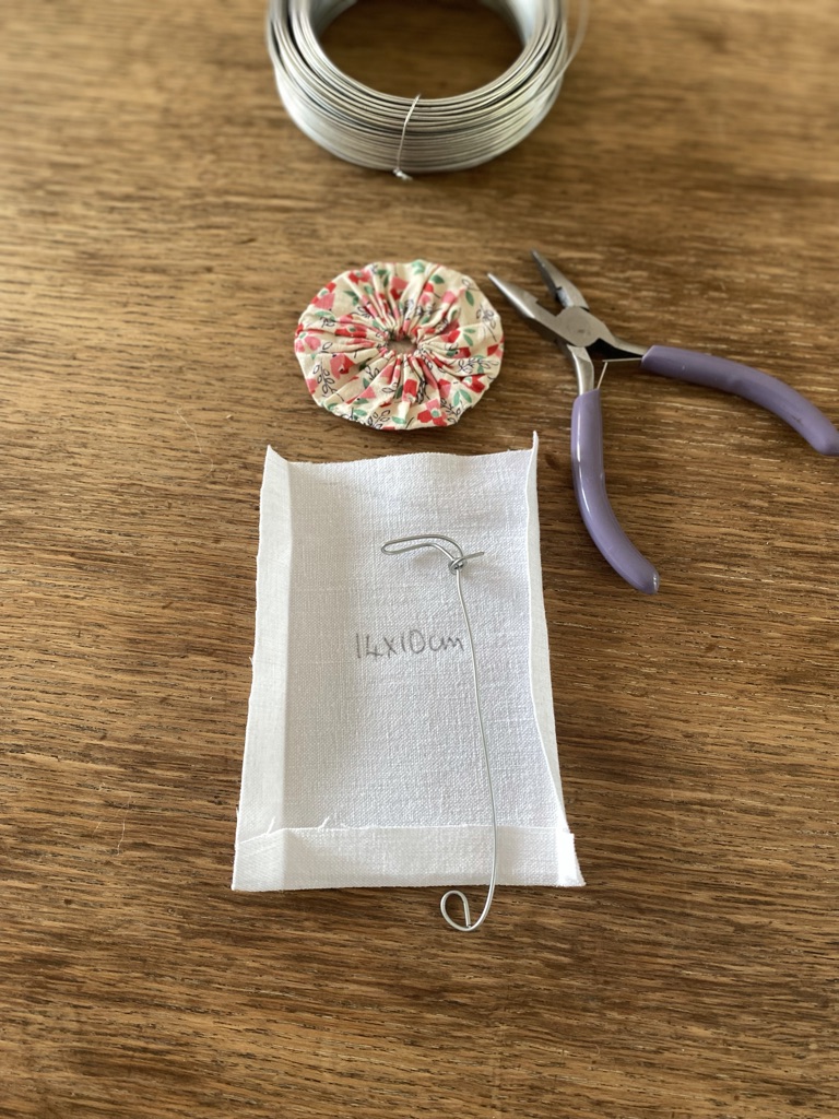 piece of white linen, off cut of wire, purple snips, suffolk puff and a roll of wire