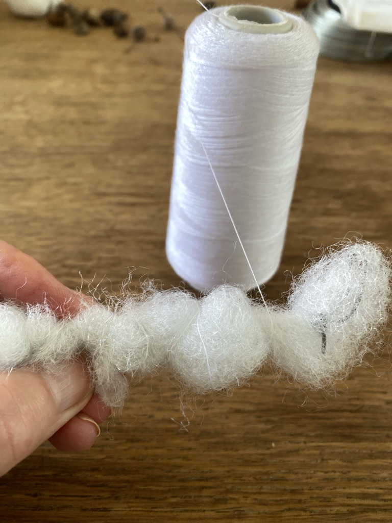 toy stuffing wrapped around wire and secured in place with roll of white thread