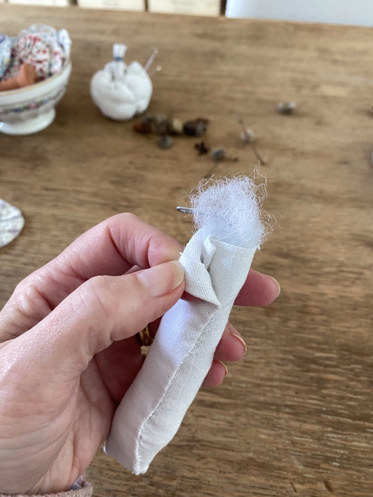 making a fabric mushroom stem with pumpkin pin cushion and bowl of suffolk puffs in background