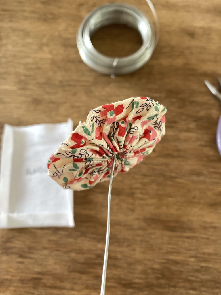 piece of white linen, off cut of wire, suffolk puff on a piece of wire