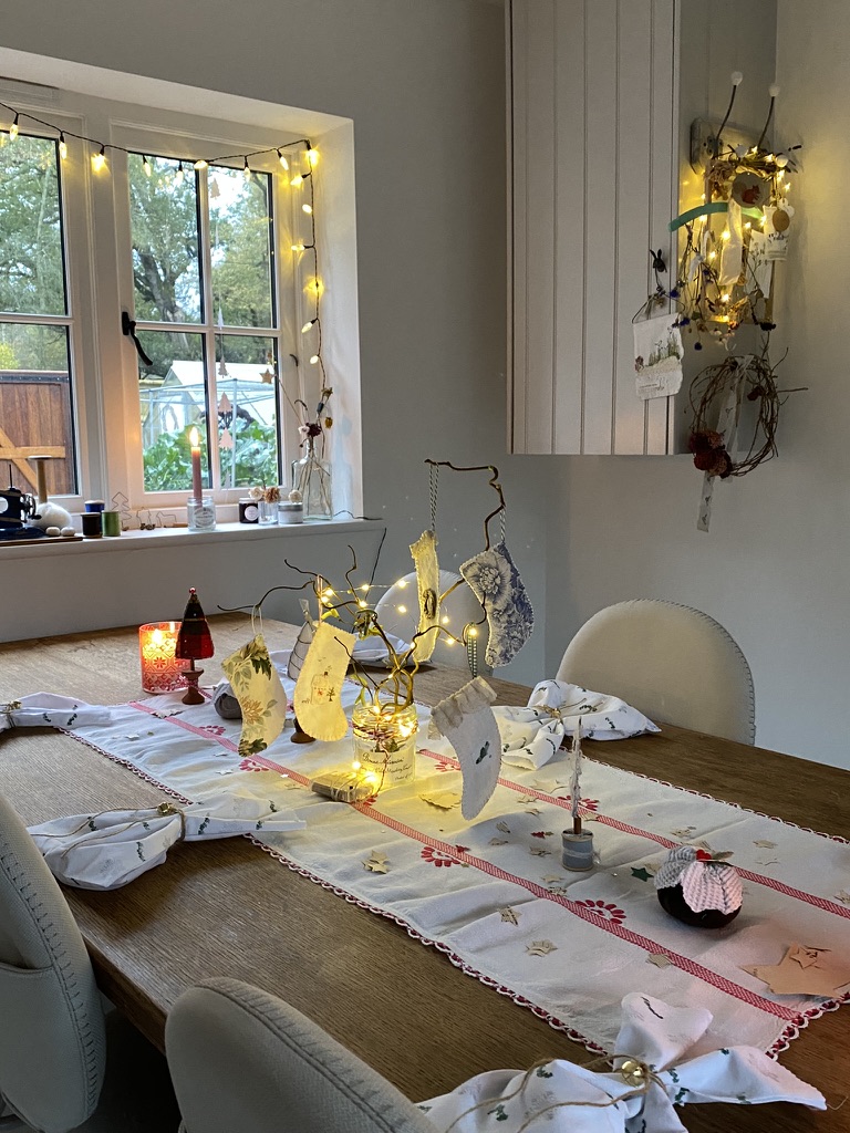 quaint cottage style craft room with table set fpr Christmas crafts and window dressed with fairy lights