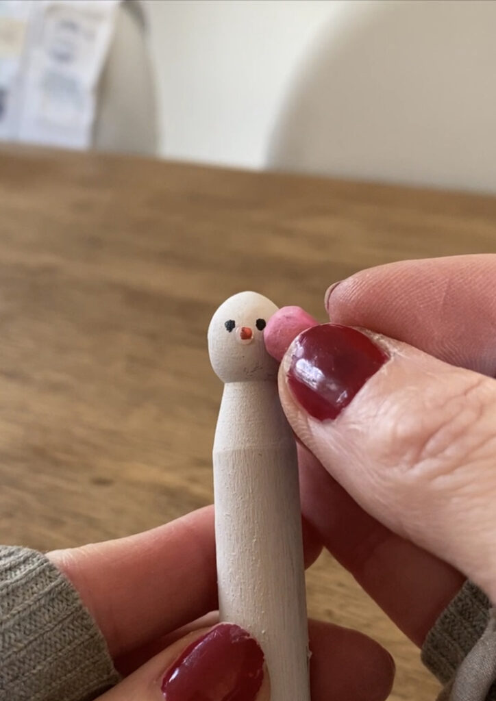 adding chalk cheeks to a dolly peg snowman