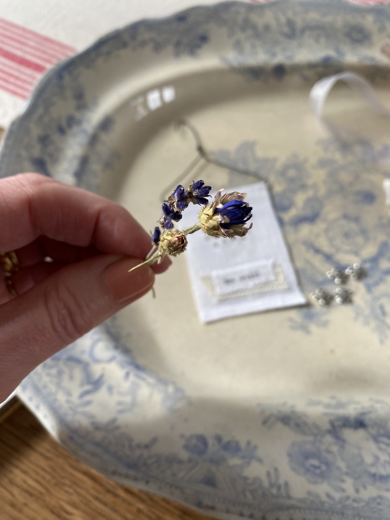 hand holds mini dried flowers to attach to bee embroidery wall hanging decoration