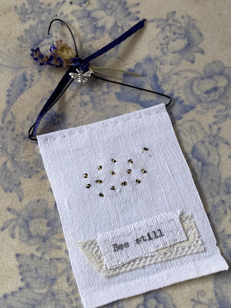 A simple bumble bee embroidery wall hanging sits on vintage blue and white plate