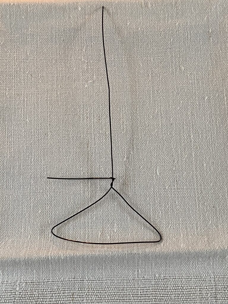 craft wire twisted into start of mini coat hanger on top of white linen