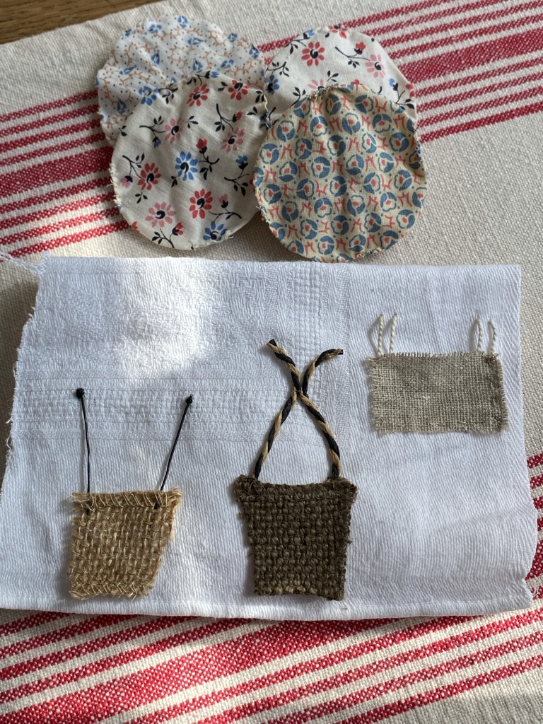 four suffolk puff yo-yos in the background of three ideas for baskets and ropes on white linen created from ribbons and fabrics