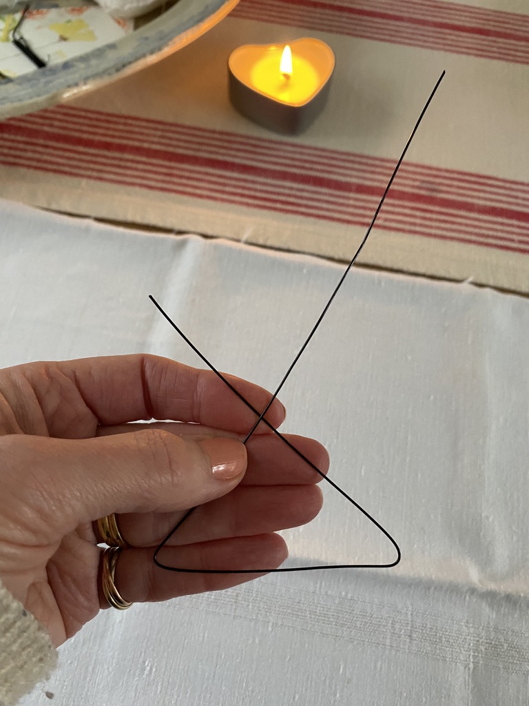 white linen, bent wire in female hand with heart shaped candle in background