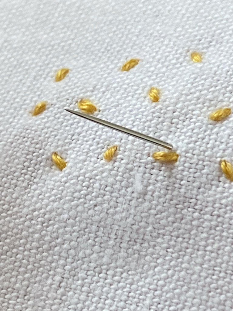 yellow stab stitches form the body of bumble bees with embroidery needle poking through fabric