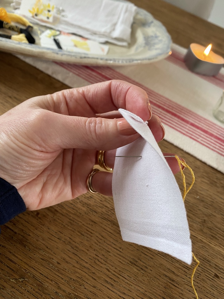 hand sewing yellow thread through white linen