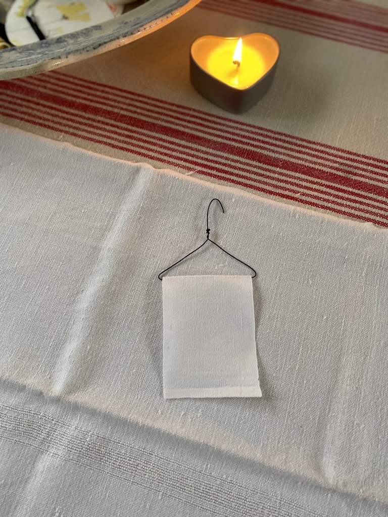 craft wire mini coat hanger with white linen and heart shaped candle in rear