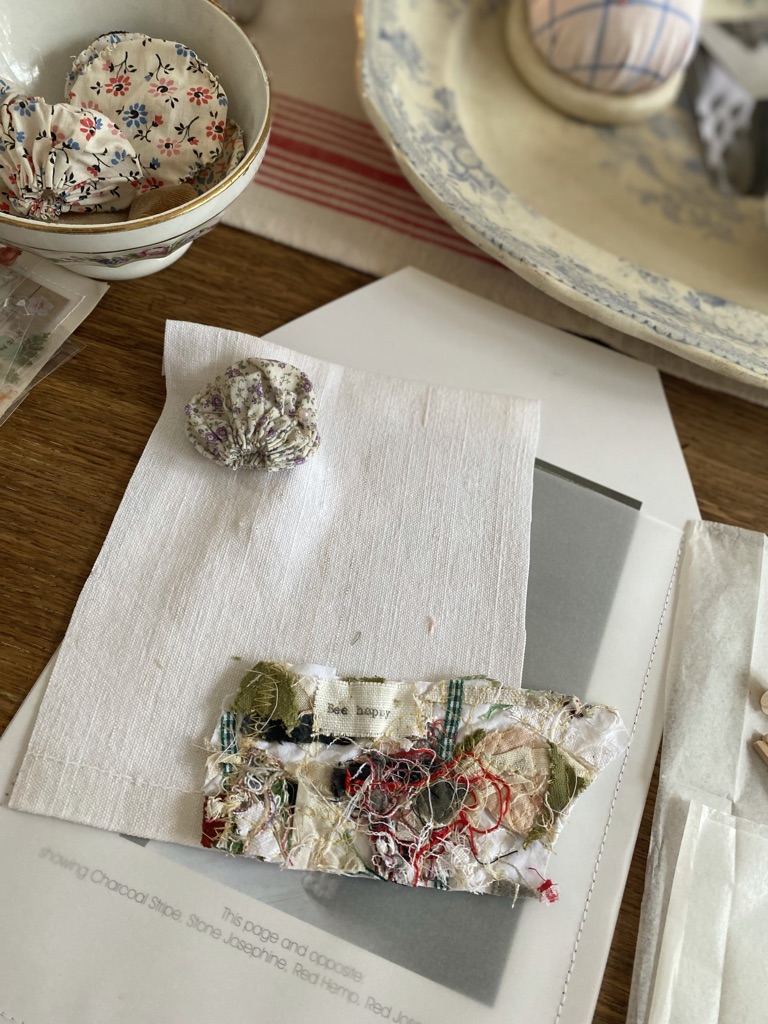 suffolk puffs fabric, paper and ephemera on top of wooden craft table