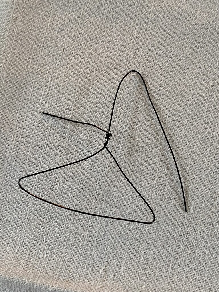 craft wire twisted into start of mini coat hanger on top of white linen