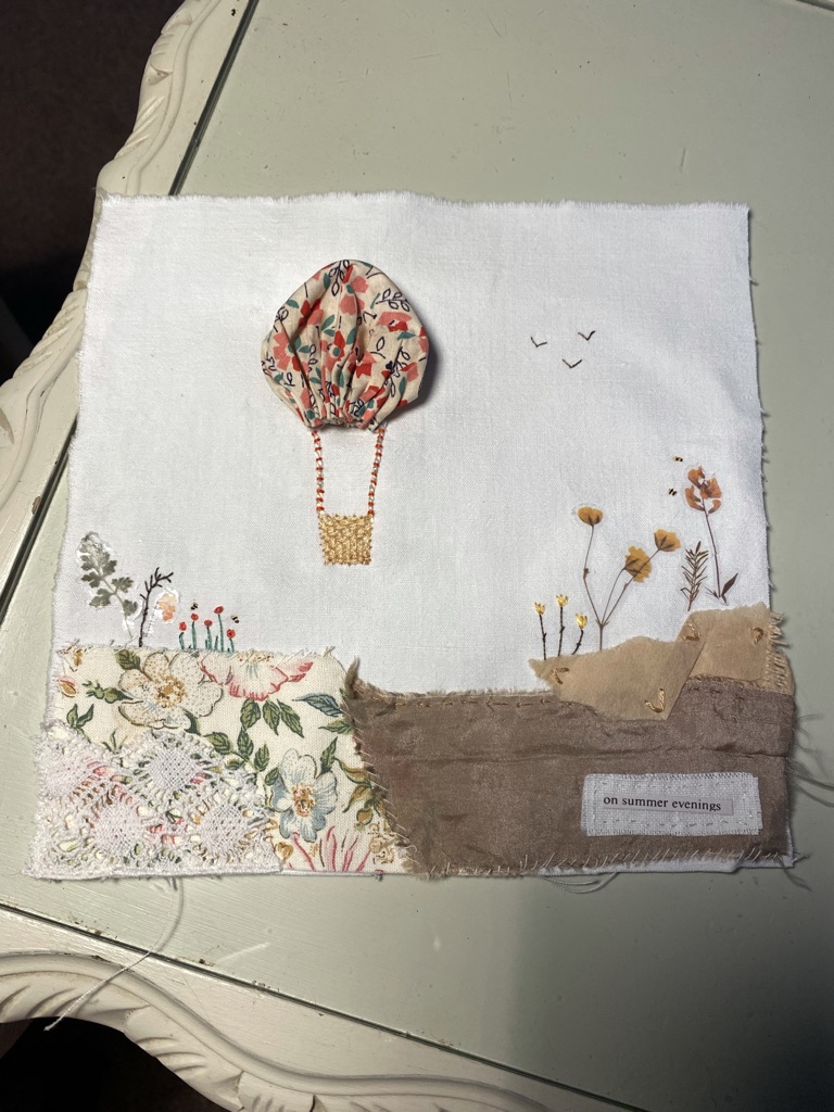 A fabric collage of a hot air balloon country scene created from a variety of crafting mediums