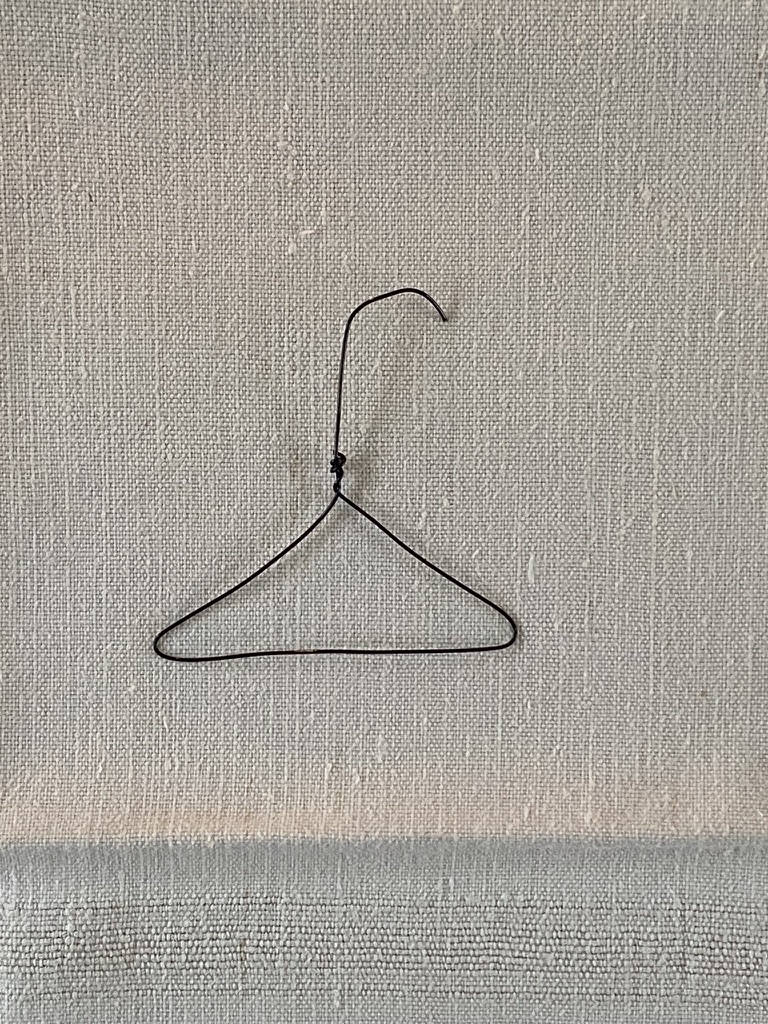 craft wire twisted into mini coat hanger on top of white linen